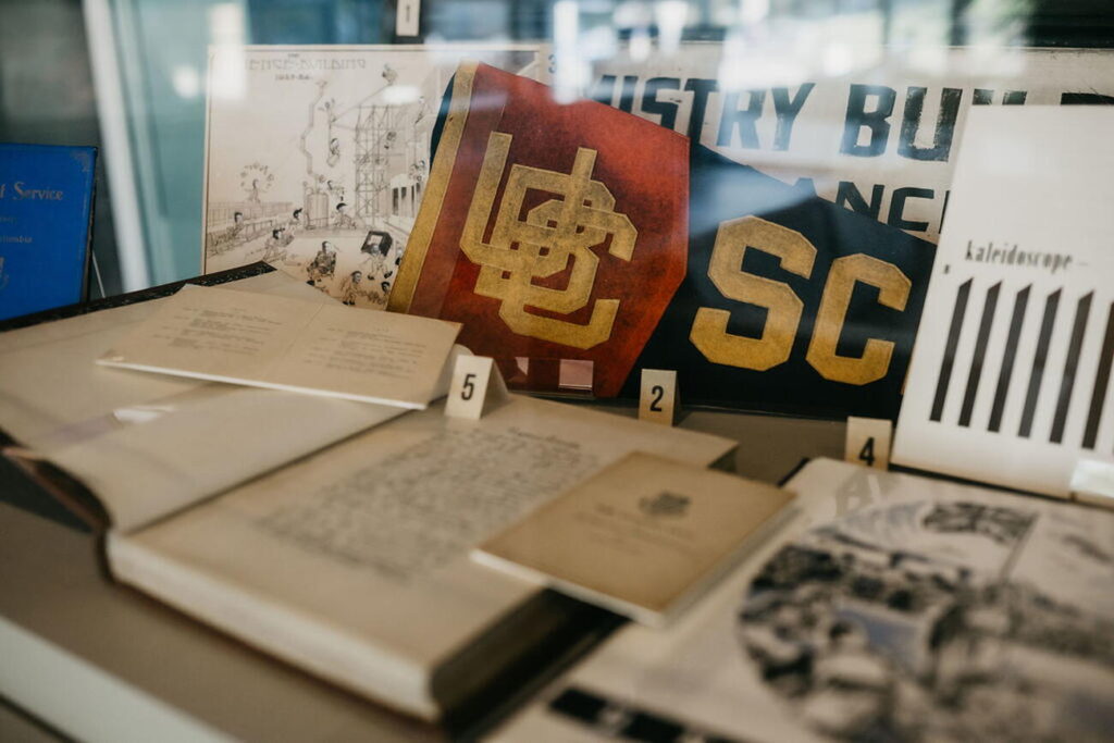 Photo of the interior of a display case showing a vintage UBC flag an books.